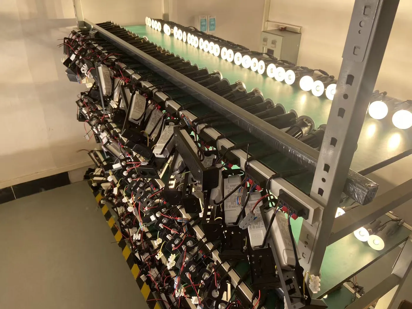 Rows of powered LED downlights and connected drivers on a KLM factory test rack