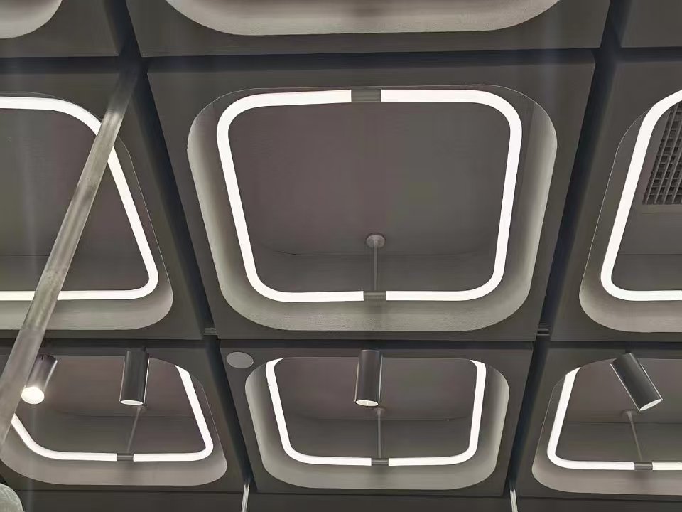 Gros plan sur un module de tube LED carré suspendu à 360° et sur l'éclairage de plafond environnant d'un commerce de détail.